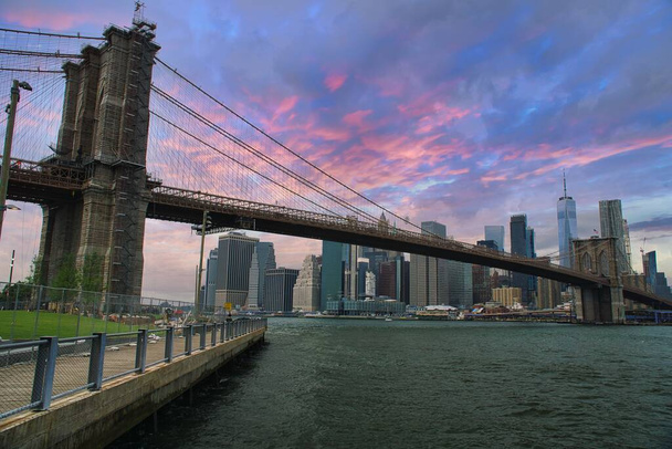 Stunning view of Manhattan skyline and Brooklyn bridge with sunset clouds in New York City, USA - Фото, изображение