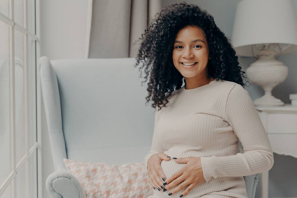 Young smiling pregnant mixed race woman touching belly - Fotografie, Obrázek