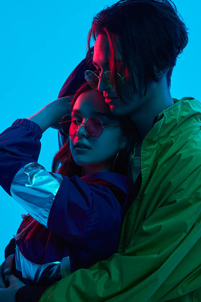 Trendy young couple hugging under neon light - Foto, imagen