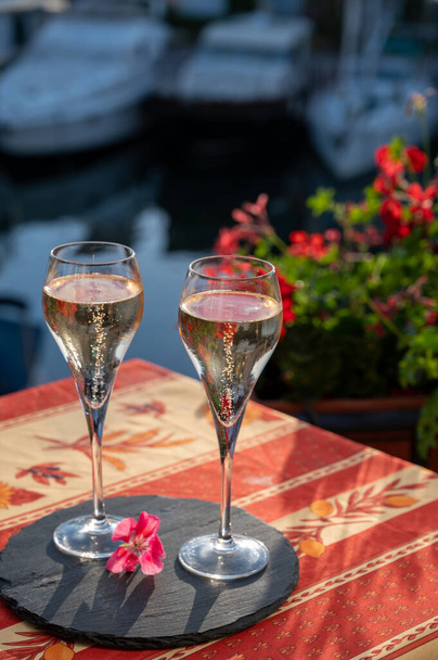 Romantický svatební večírek se dvěma sklenicemi bílého studeného šampaňského, letními květinami a výhledem na jachty a domy Port Grimaudu, Francouzská riviéra, Francie - Fotografie, Obrázek