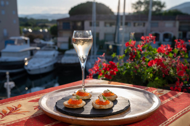Beber champán blanco frío al atardecer con caviar rojo y ver Port Grimaud cerca de Saint-Tropez en verano - Foto, Imagen