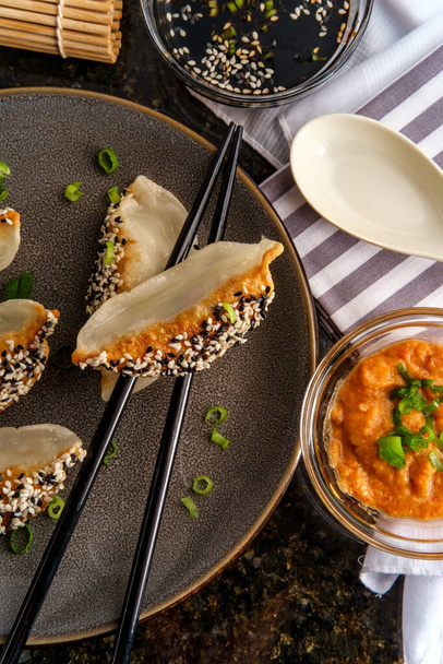 Dumplings de wonton de verduras fritas chinas con semillas de sésamo blanco y negro y salsa de satay de cacahuete para mojar  - Foto, Imagen