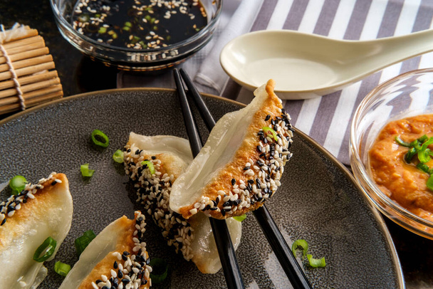 Chinese gebakken groente wonton knoedels met zwart-wit sesamzaad en pinda satésaus voor het dompelen  - Foto, afbeelding