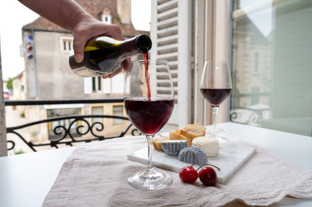 Γευσιγνωσία του βυσσινί κόκκινο κρασί από αμπελώνες grand cru pinot noir με γαλλικά κατσικίσια τυριά και θέα στην παλιά πόλη δρόμο στη Βουργουνδία Cote de Nuit περιοχή του κρασιού, Γαλλία - Φωτογραφία, εικόνα