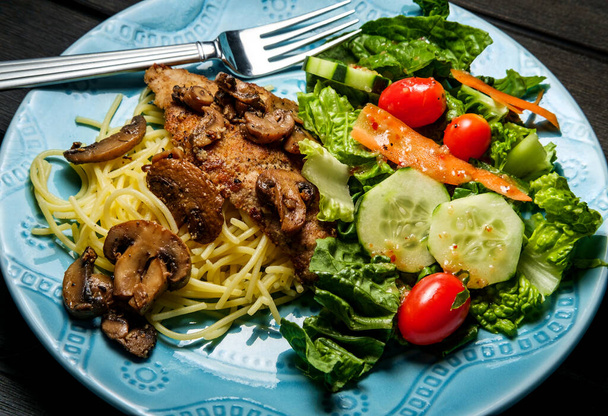 Włoska cielęcina marsala serwowana nad spaghetti z sałatką ogrodową - Zdjęcie, obraz