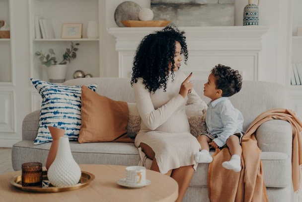 Portrét milující afro americké těhotné matky vysvětlující malého syna o svém těhotenství - Fotografie, Obrázek