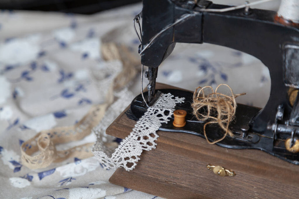 Vintage manual sewing machine and a skein of thread on a white fabric background with a blue pattern close-u - Foto, imagen