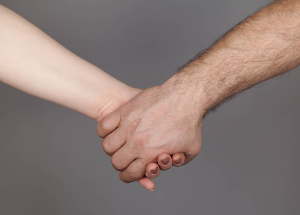 Mani dell'uomo e della donna che tengono insieme, sfondo grigio. - Foto, immagini