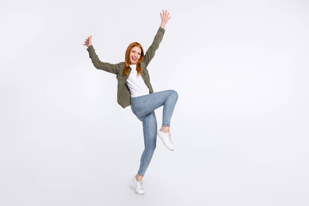 Взгляд в полный рост на привлекательную жизнерадостную девушку, танцующую прыгающую, веселясь на светлом цветовом фоне - Фото, изображение