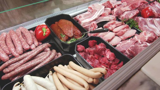 oddělení masa vystavovat police s výběrem typických čerstvých syrových masových plátků a různých uzenářských výrobků na trhu nebo v supermarketu chlazené zázemí. - Fotografie, Obrázek