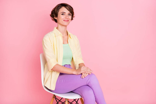 Photo of charming cute young lady dressed yellow shirt sitting chair isolated pink color background - Zdjęcie, obraz