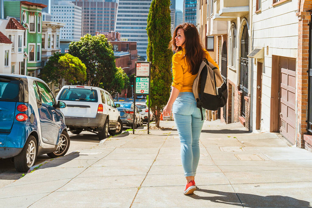 Linda joven camina a lo largo de una hermosa calle con vistas a la Torre Transamerica en San Francisco - Foto, imagen
