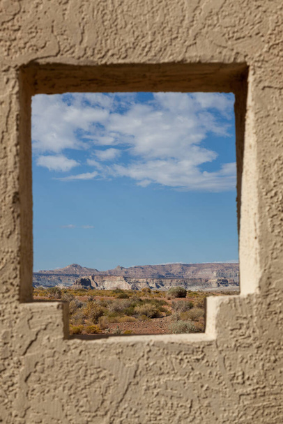 A window carved in a plaster wall near a rest stop area by Wahweap Bay in Lake Powell with a picturesque view of the distant landscape and sky. - Photo, Image