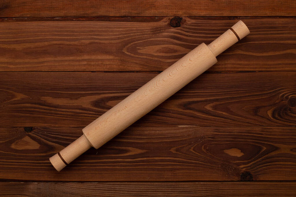 Traditional handmade organic wooden culinary dough rolling pin for cooking on a brown background with wooden texture. Kitchenware. Top view, Close Up - Photo, Image
