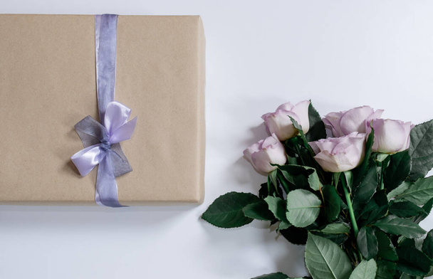 Μπουκέτο από βιολετί τριαντάφυλλα με κουτί δώρου στο λευκό φόντο, πάνω όψη, αντίγραφο χώρου. - Φωτογραφία, εικόνα