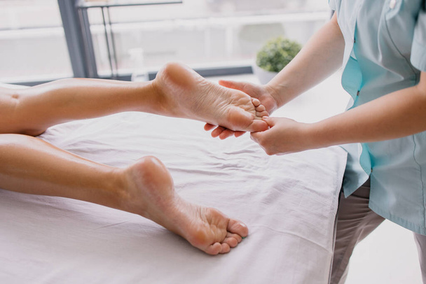 Foot massage close-up. Spa salon self-care relax. Kneading the feet. Pleasant pleasures. The masseur is working. Treating fatigue and leg pain. Health care acupuncture. massaging thumb foot - Fotografie, Obrázek