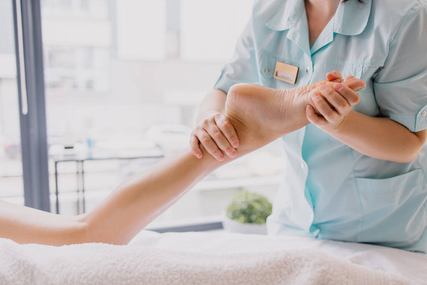 Foot massage close-up. Spa salon self-care relax. Kneading the feet. Pleasant pleasures. The masseur is working. Treating fatigue and leg pain. Health care acupuncture. massaging Heel fingers foot - Foto, imagen