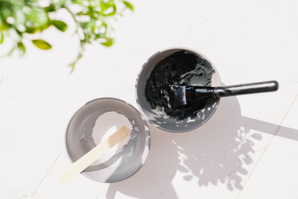 process of mixing mud for a face mask. Spa salon relaxation mood. Caring for the health of the skin care. Home procedure. Black and white clay ingredients different minerals compositions. Cosmetology - Zdjęcie, obraz