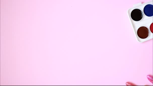 stop motion layout sobre um tema escolar em um fundo rosa com aquarelas, canetas e clipes de papel. Vista superior com espaço de cópia. Voltar para a escola flat lay no fundo azul e rosa - Filmagem, Vídeo