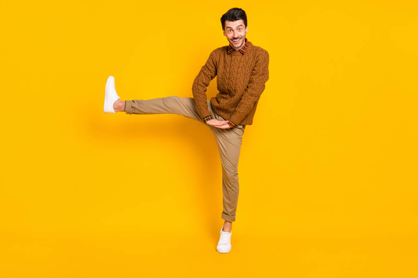 Full body photo of satisfied young person raise lag beaming smile wear sweater isolated on yellow color background - Φωτογραφία, εικόνα