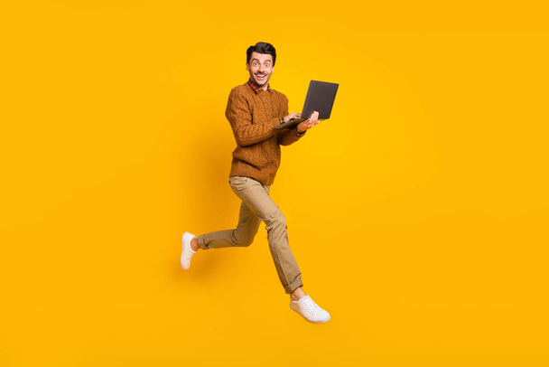 Full size profile photo of impressed nice brunet man hold laptop wear sweater isolated on yellow background - Foto, immagini
