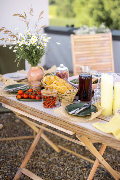 Mesa de madera bellamente servida con comida y platos en estilo boho natural al aire libre - Foto, imagen