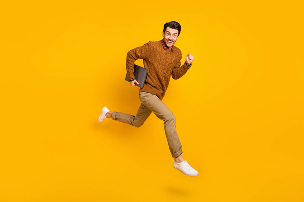 Full size profile photo of impressed nice brunet man hold laptop run wear sweater isolated on yellow background - Fotó, kép