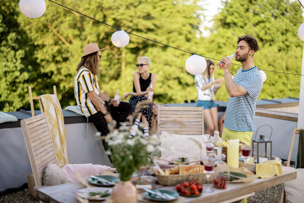 Giovani amici alla moda che fanno una cena festiva sulla terrazza sul tetto - Foto, immagini