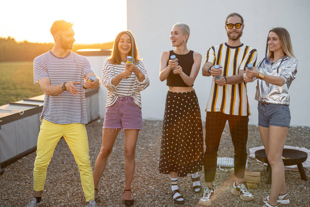 Young stylish friends celebrating on the rooftop at sunset - Foto, imagen