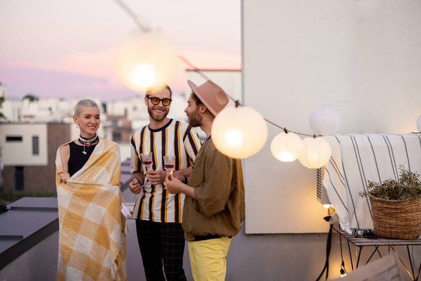 Friends have fun on a rooftop party at dusk - Photo, Image