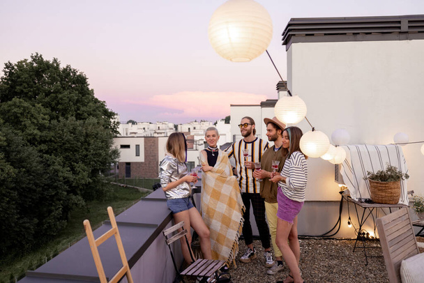 Друзья веселятся на вечеринке на крыше в сумерках - Фото, изображение