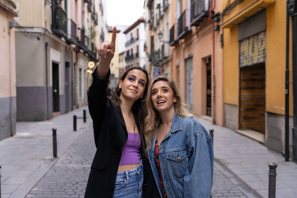 Two girls smiling and looking around while having a walk in the city center - Photo, Image