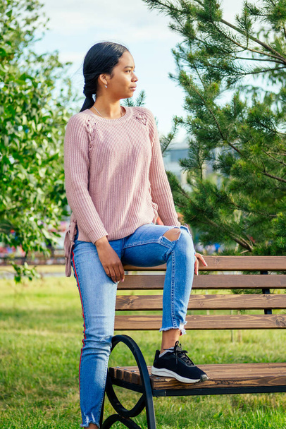 Vietnamese woman in pink sweater sitting on the bench - Valokuva, kuva