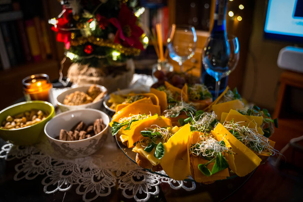 ビュッフェテーブルでのワインのためのスナック。クッキー、ナッツ、サーモンとチーズとナチョスのサンドイッチなどの冷たい軽食。クリスマスや新年のお祝いの概念を示すパーティースナックテーブル - 写真・画像