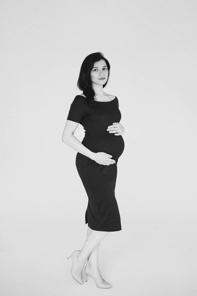 feliz mãe grávida tocando sua barriga e posando para a câmera - Foto, Imagem