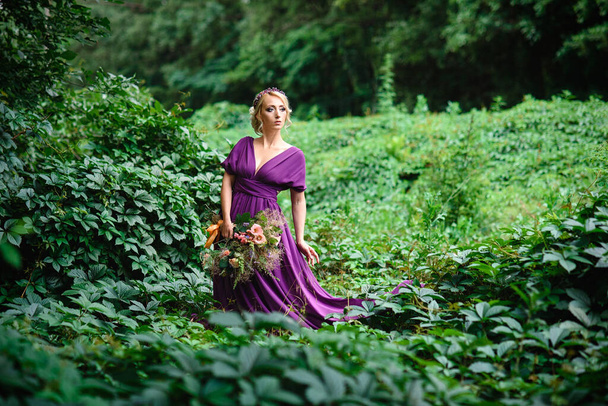 Lány modell szőke egy orgona ruha egy csokor zöld erdő - Fotó, kép