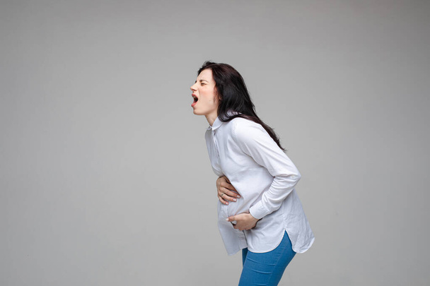 beautiful young pregnant woman screaming beacuse of a strong stomach ache - Photo, Image