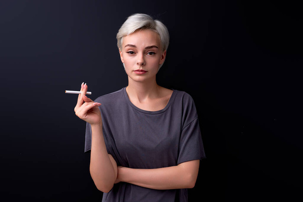 Confident female holding Cigarette in hands, calm and relaxed, using tobacco, isolated on black - Fotografie, Obrázek