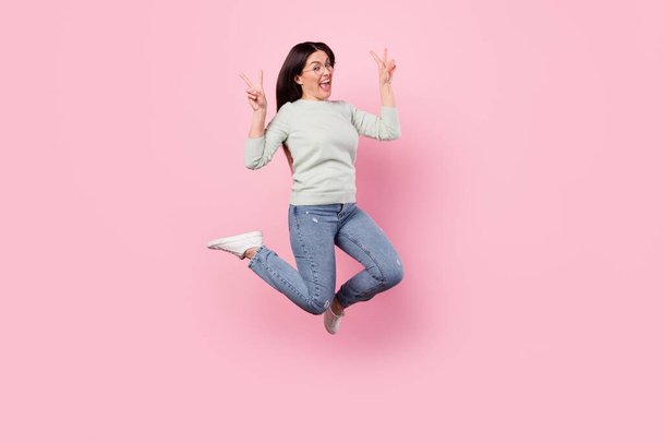 Full body photo of cheerful positive woman jump up air show v-sign good mood isolated on pink color background - Zdjęcie, obraz