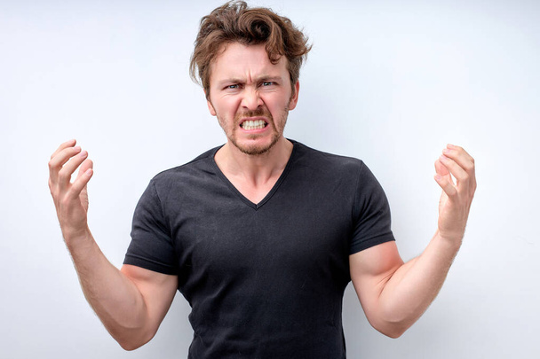 Young angry man wearing t-shirt standing over isolated white background crazy and mad - Foto, Bild