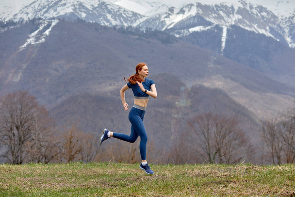 Young woman running outdoors in nature in mountians. Fitness and healthy lifestyle concept. - Foto, Bild