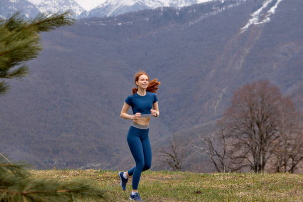 Jogging is healthy for active lifestyle runners. Redhead woman in sportswear outdoors - Фото, изображение