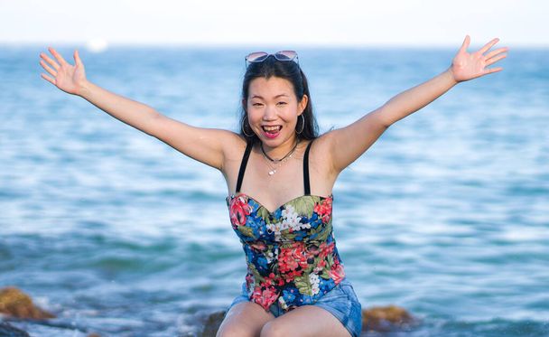 holidays lifestyle portrait of young Asian woman by the  sea -  happy and beautiful Korean girl  enjoying beach vacation trip relaxed and cheerful at beach rock cliff - Photo, Image