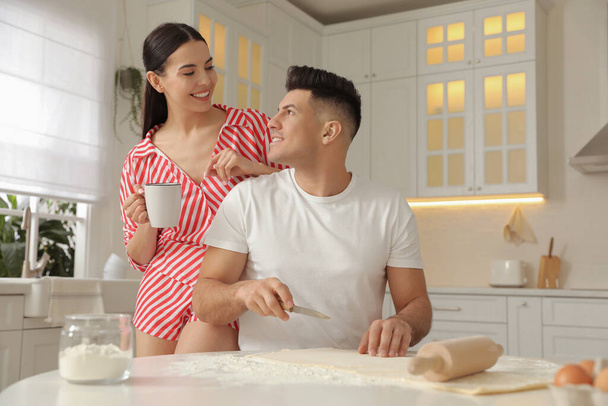 Happy couple wearing pyjamas and cooking together in kitchen - Foto, imagen