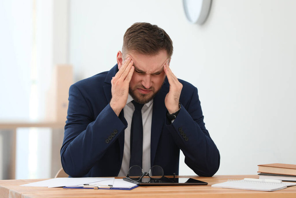 Man suffering from migraine at workplace in office - Фото, зображення