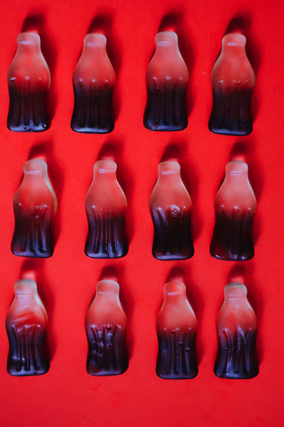 Cola jelly gummy candies in four rows at red background - Foto, imagen