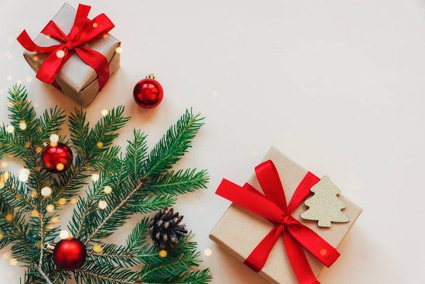 Twee geschenken en groene sparren takken met versieringen op een beige achtergrond. Kerstconcept. Bovenaanzicht, flat lay, kopieerruimte. - Foto, afbeelding
