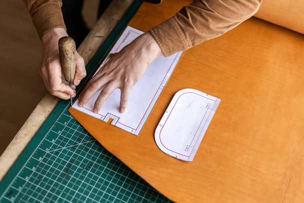 Mannelijke looierij maken snijschema van zak werken in lederen werkplaats. Handgemaakt maken - Foto, afbeelding