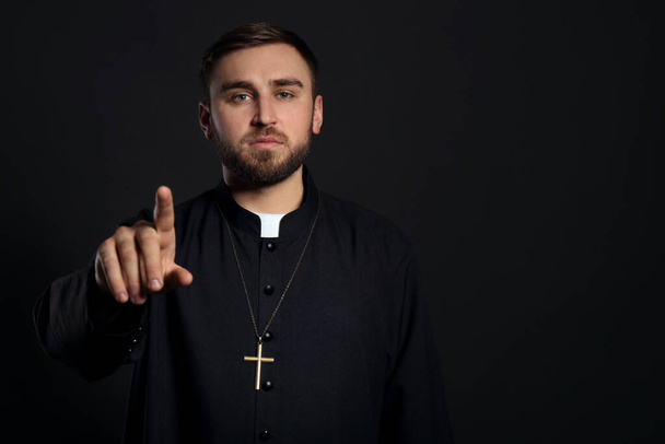 Priest wearing cassock with clerical collar on black background. Space for text - Foto, Imagem