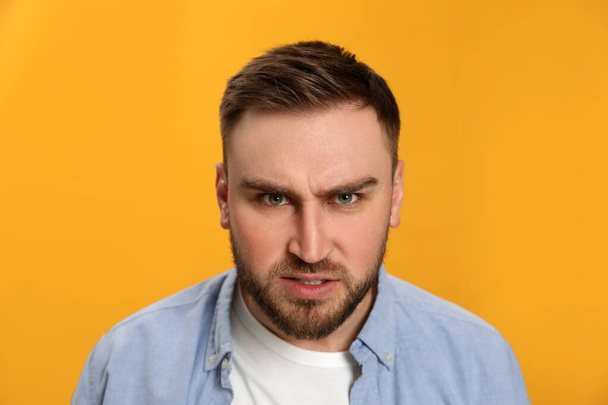 Angry young man on yellow background. Hate concept - Фото, изображение